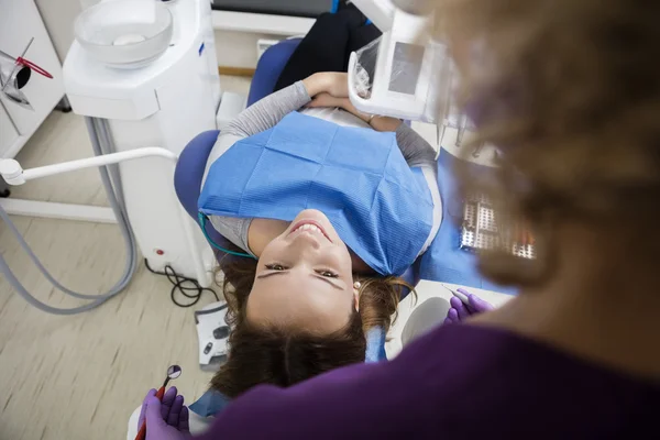 Mujer sonriente mirando al dentista mientras está tumbada en la silla — Foto de Stock