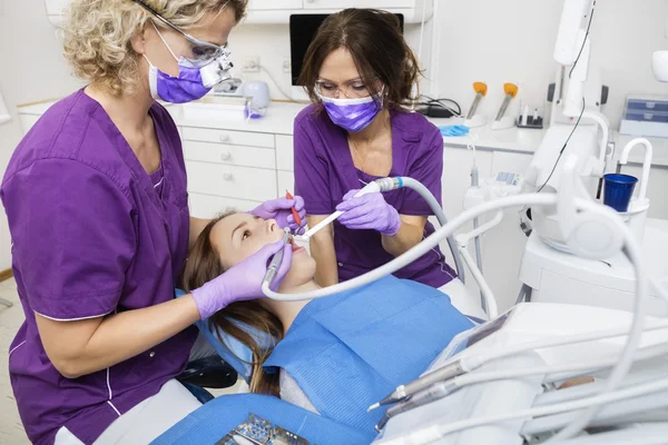 Dentistas que trabalham em dentes de pacientes jovens — Fotografia de Stock