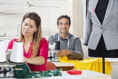 Smiling Tailor Sitting At Workbench In Factory clipart