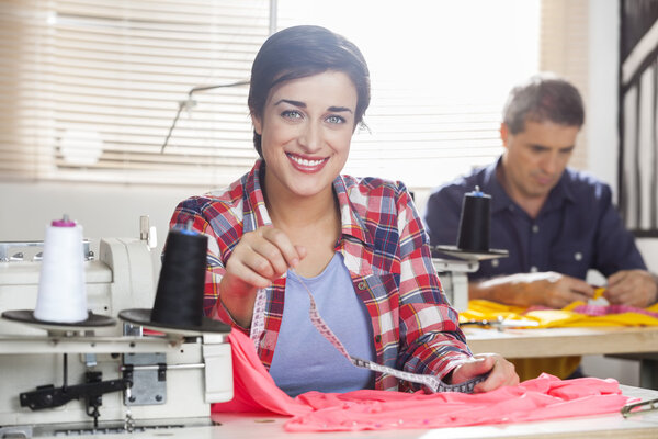 Smiling Tailor Holding Measure Tape At Workbench
