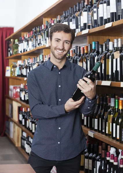 Leende kund håller vin flaska i butik — Stockfoto