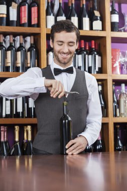 Şarap şişesi açmak için tirbuşon kullanarak barmen