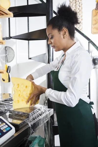 Vendedora de embalaje de queso en el mostrador en la tienda de comestibles —  Fotos de Stock