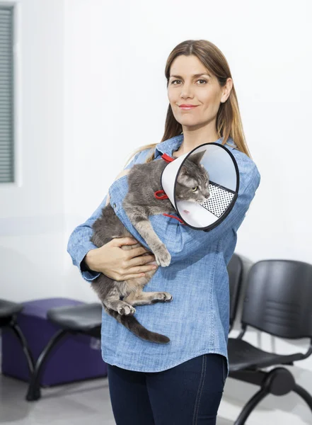 中期的成年女性在诊所抱着只猫带锥 — 图库照片