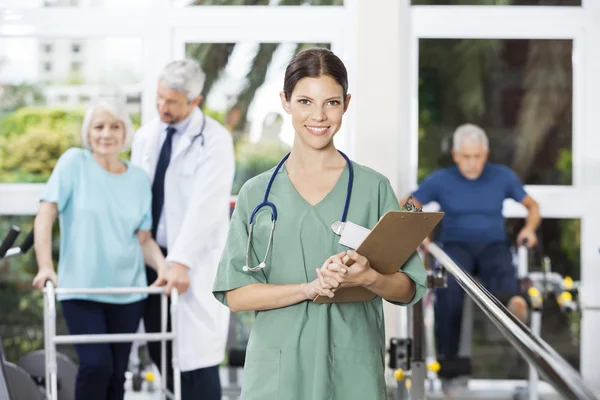 Lächelnde Physiotherapeutin mit Klemmbrett in der Hand — Stockfoto