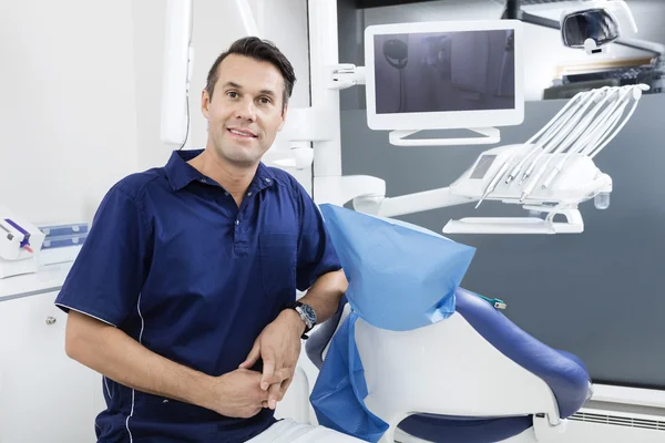 Впевнений Чоловік стоматолог спирається на стілець в клініці — стокове фото