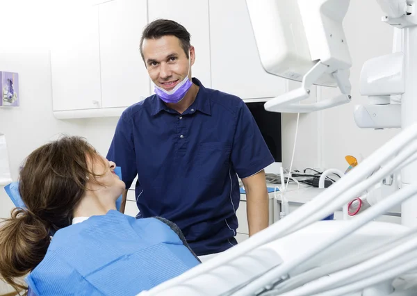 Glimlachend mannelijke tandarts met vrouwelijke patiënt In kliniek — Stockfoto