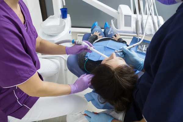 Paciente feminina sendo assistida por dentistas na clínica — Fotografia de Stock