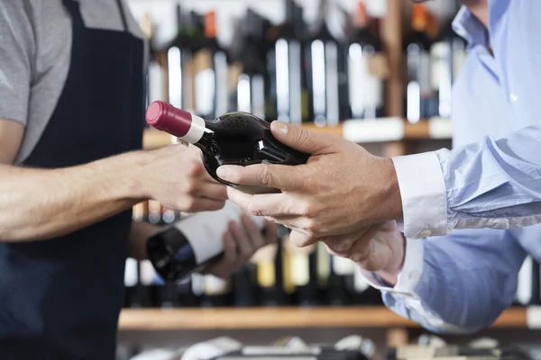 Midsection do cliente e vendedor com garrafas de vinho — Fotografia de Stock
