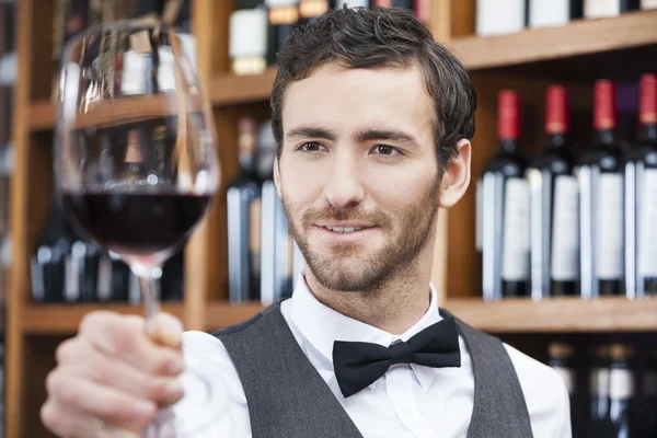 Barman zkoumání červené víno ve skle v obchodě — Stock fotografie