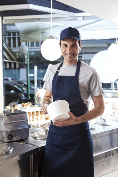 Sorrindo trabalhador segurando tigela no salão de sorvete — Fotografia de Stock