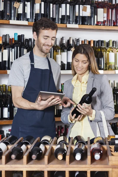 Souriant vendeur montrant des informations sur le vin au client sur numérique — Photo