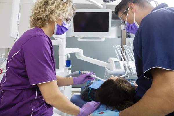 Zubař a asistent zkoumání starší pacient na klinice — Stock fotografie
