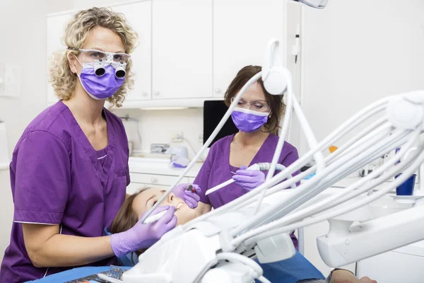 Dentista e colega trabalhando em jovens mulheres dentes — Fotografia de Stock