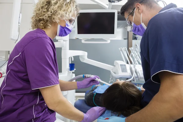 Dentist And Assistant Examining Mature Patient In Clinic Stock Photo