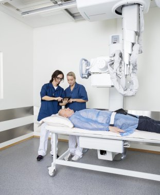 Doktorlar dijital Tablet kullanarak süre Xray makine altında yatan adam