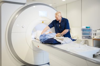 Male Radiologist Preparing Young Woman For MRI Scan clipart
