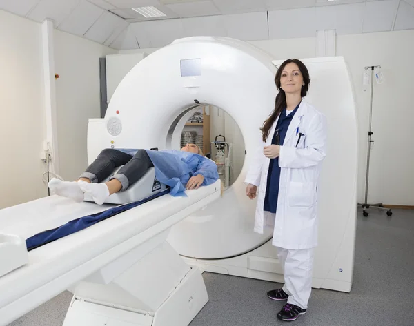 Врач, стоящий рядом с пациентом, лежащим на аппарате МРТ в больнице — стоковое фото