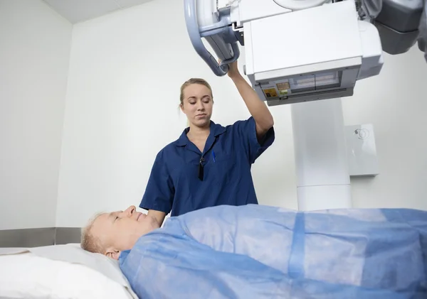 Radiologista ajustando a máquina de raios X sobre o homem — Fotografia de Stock