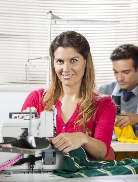 Zufriedene Schneiderin arbeitet an Werkbank in Fabrik — Stockfoto