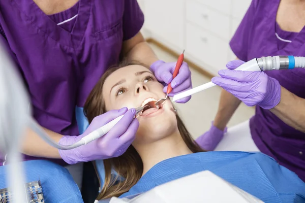 Buik van volwassen tandartsen werken aan jonge vrouwelijke patiënten — Stockfoto