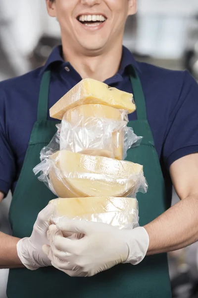 Verkäufer trägt Stapel Käse im Geschäft — Stockfoto