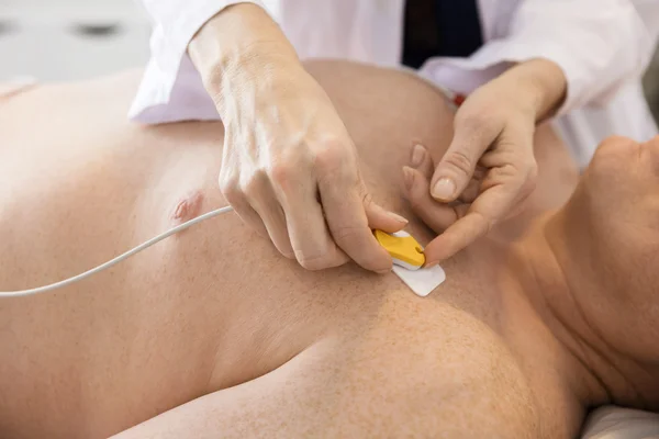 Ärzte befestigen Elektroden an der Brust des Patienten — Stockfoto