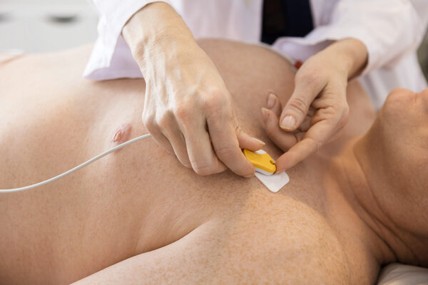 Doctors Hands Attaching Electrodes On Patients Chest