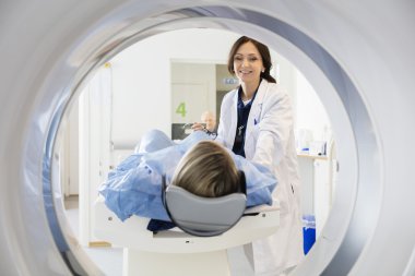 Female Doctor Looking At Patient Undergoing CT Scan clipart