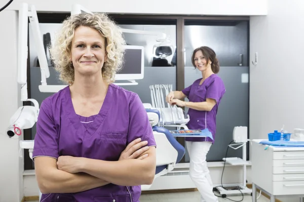 Braços de pé assistentes cruzados com colegas trabalhando em dentis — Fotografia de Stock