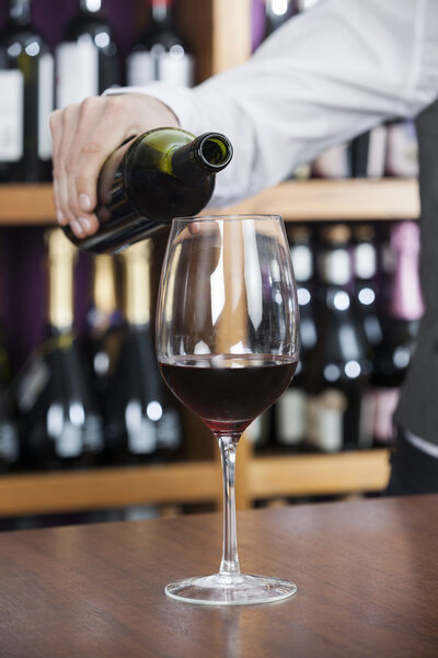 Cropped Image Of Bartender Pouring Red Wine In Glass