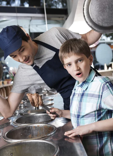 Удивленный мальчик с шоколадным мороженым, стоящий рядом с официантом — стоковое фото