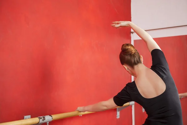 Bailarina estirándose en la barra en el estudio de ballet — Foto de Stock