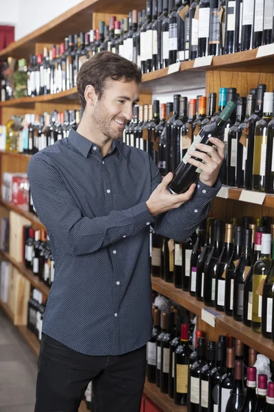 Cliente mirando botella de vino en la tienda —  Fotos de Stock