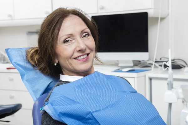 Lachende patiënt zit bij tandartsen kliniek — Stockfoto