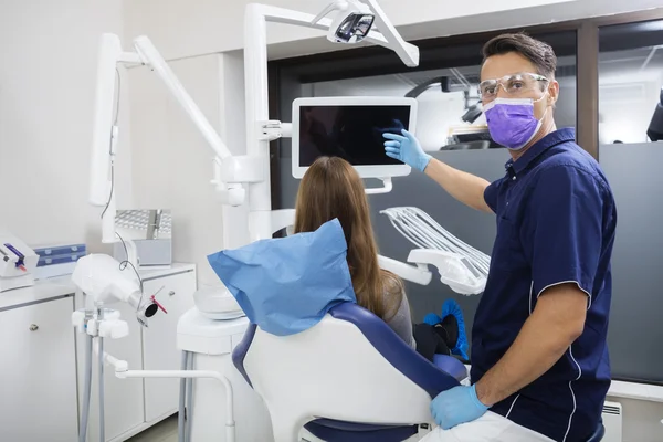 Porträt eines Zahnarztes, der Patientin leeren Bildschirm zeigt — Stockfoto