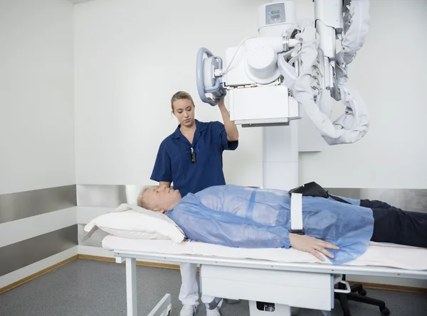 Doctor ajustando la máquina de rayos X sobre el paciente — Foto de Stock