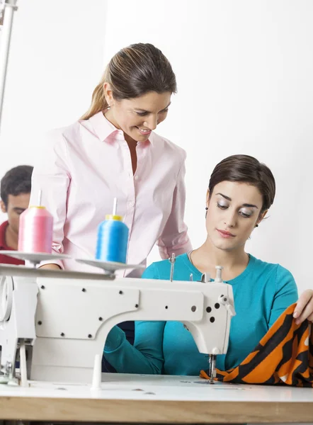 Sastre mirando costura de colegas en fábrica — Foto de Stock