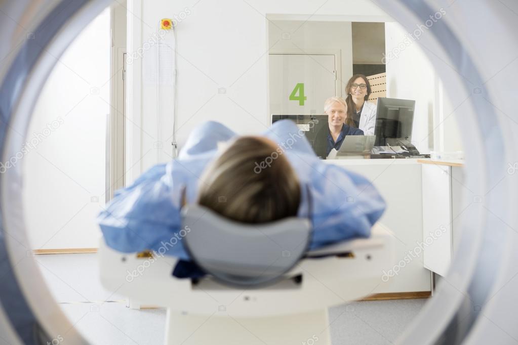 Doctors Looking At Patient Undergoing CT Scan