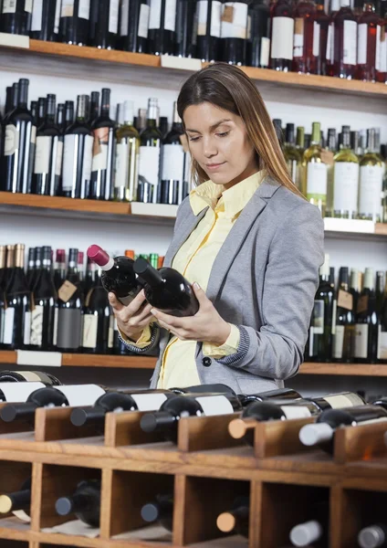Kvinna som tittar på vinflaskor i butik — Stockfoto