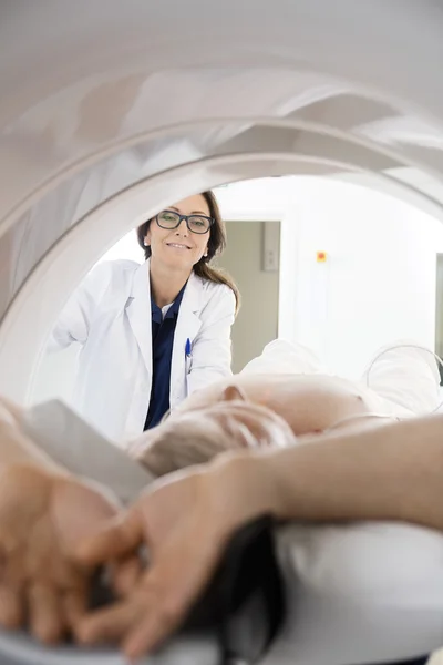 Médico olhando para o homem submetido a tomografia computadorizada — Fotografia de Stock