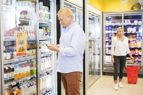 Homem usando telefone celular no supermercado — Fotografia de Stock