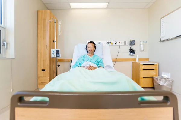 Paciente com os olhos fechados em cama de hospital — Fotografia de Stock