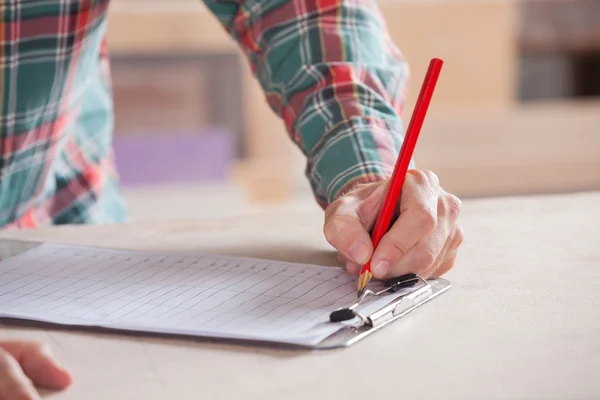 Bijgesneden afbeelding van timmerman schrijven van notities op Klembord — Stockfoto