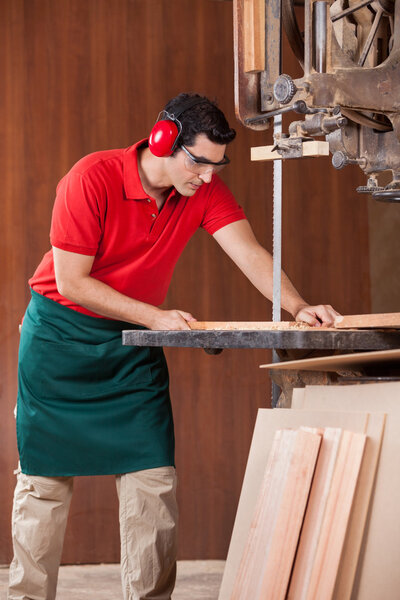 Carpenter Using Bandsaw To Cut Wooden Plank