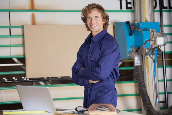 Gelukkig timmerman met gekruiste aan tafel armen — Stockfoto