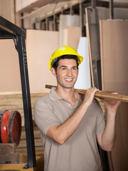 Carpenter Carrying Plank While Looking Away Stock Image