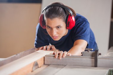 Female Carpenter Cutting Wood With Tablesaw clipart