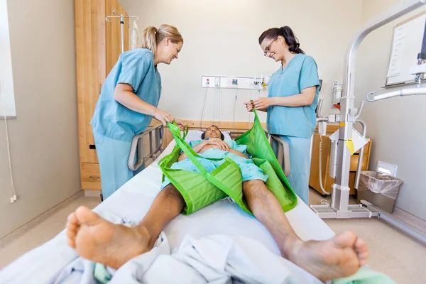 Infirmières préparant patient masculin avant de le transférer sur fronde L — Photo