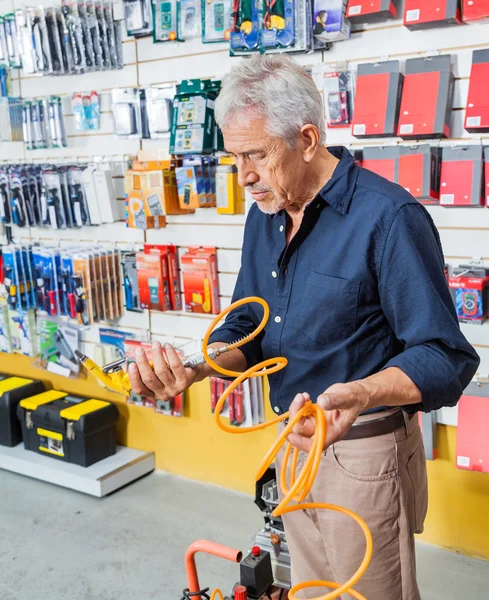 Hombre analizando la manguera del compresor de aire en tienda — Foto de Stock